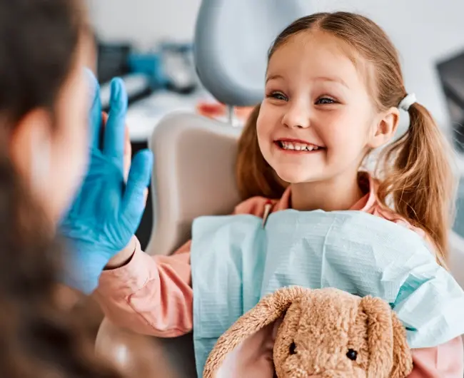 Smiling child giving a high five to a kids friendly dentist in Newport Beach during a dental visit