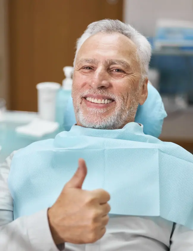 Senior male patient smiling in dental chair after preventive treatment in Newport Beach.