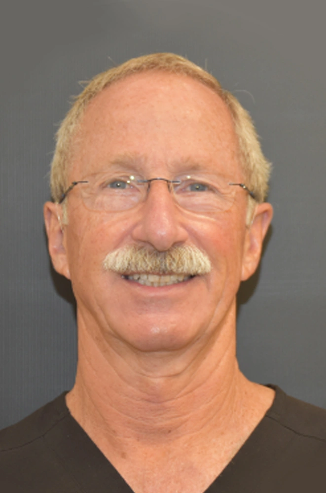 Professional headshot of middle-aged man with glasses in dental practice setting